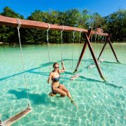 Woman in lake Bacalar on a swing